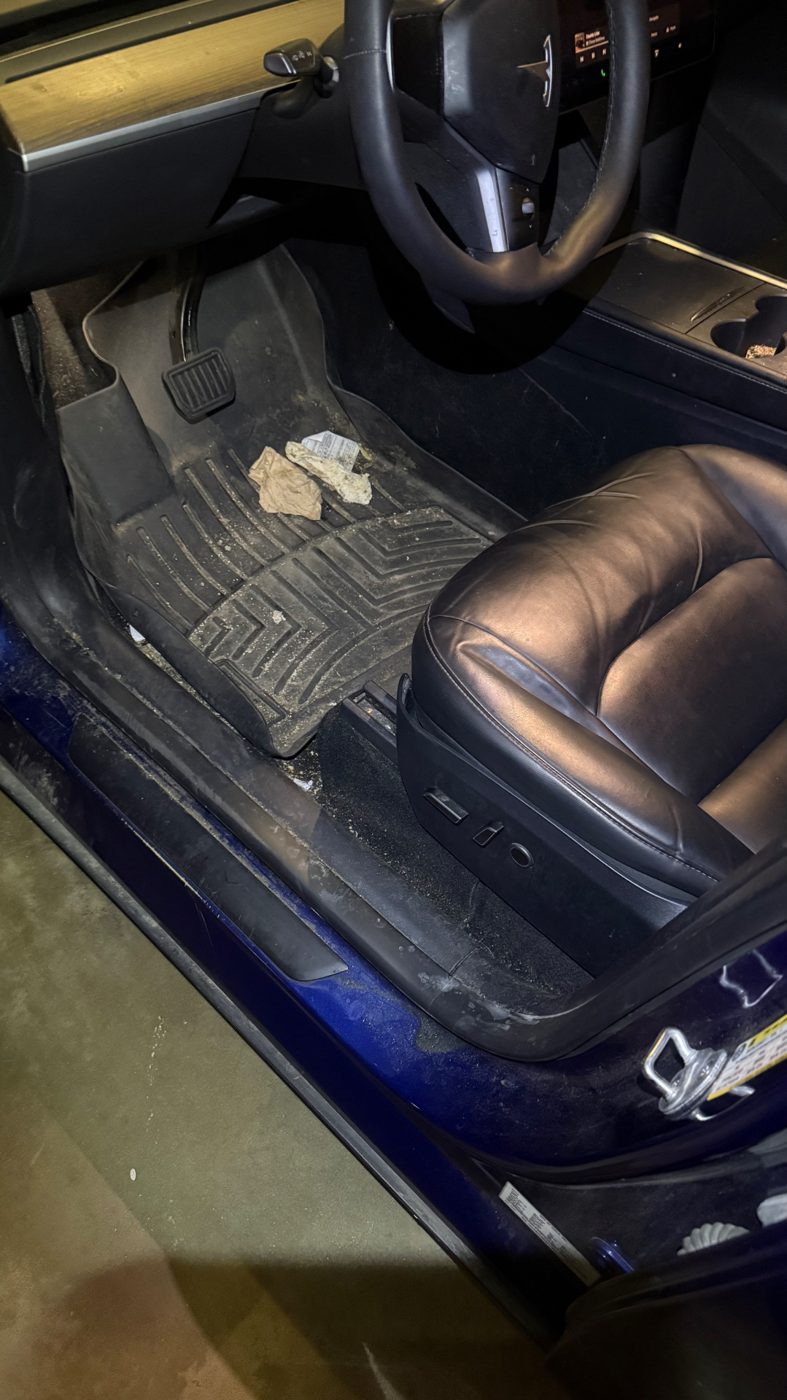 Tesla Model 3 floor mat with trash and dirt before an interior detail
