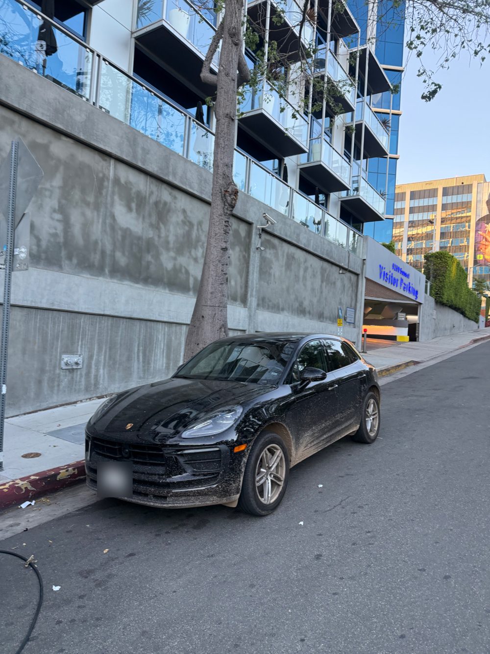 Black Porsche Macan covered in mud and dust before an exterior detail