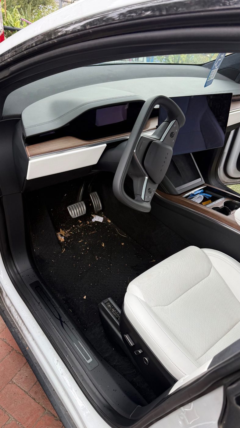 Tesla Model X driver footwell with debris on the carpet before an interior detail